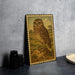 a framed illustration of an owl on a rock, placed on a table next to some black camera lenses.