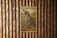 A California Quail postage stamp is displayed on a wooden wall.