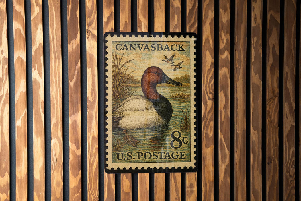 A U.S. postage stamp featuring a duck swimming in a pond, mounted on a wooden wall.