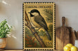 A decorative metal stamp featuring a black-and-white illustration of a Carolina Chickadee perched on a branch, with the text "Carolina Chickadee USA" printed on it. The stamp is displayed on a shelf next to a wooden cutting board and a potted plant.