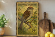 A vintage postage stamp featuring a chipping sparrow perched on a branch, with a potted plant and wooden cutting board in the background.