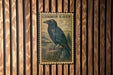 a vintage-style postage stamp with a black raven illustration, mounted on a wooden wall.