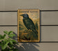 a framed illustration of a black raven perched on a rock, with a plant to the left of the frame.