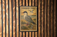a postage stamp with a bird illustration, mounted on a wooden wall.