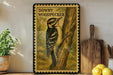 A framed illustration of a Downy Woodpecker is displayed on a wall, with a wooden cutting board and a potted plant to the side.