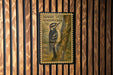 A postage stamp featuring a woodpecker is displayed on a wooden wall.