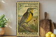 A vintage-style postage stamp from the United States, featuring a yellow and black bird perched on a branch, is displayed on a shelf next to a wooden cutting board and some potted plants.