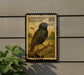 a postage stamp with a bird on it, mounted on a wall next to a plant.