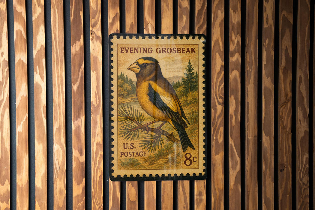 A U.S. postage stamp featuring a yellow and black bird perched on a branch, with the text "Evening Grosbeak" and "U.S. POSTAGE" printed on it.