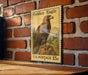 A vintage U.S. postage stamp featuring a golden eagle is displayed on a brick wall.