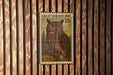 A postage stamp featuring a great horned owl is displayed on a wooden wall.