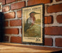 A vintage postage stamp featuring a heron is displayed on a brick wall.