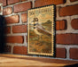 A metal stamp featuring a bird, likely a killdeer, is mounted on a brick wall.