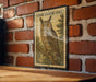 A framed illustration of a long-eared owl is displayed on a brick wall, with a wooden table below it.