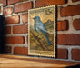 A U.S. postage stamp depicting a blue bird, specifically a mountain bluebird, perched on a branch against a brick wall.