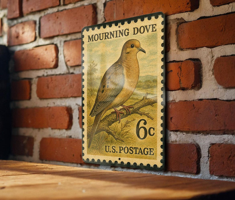 A vintage postage stamp featuring a mourning dove is displayed on a brick wall.