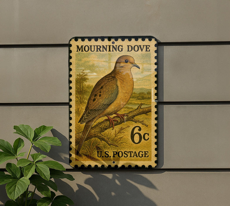 A postage stamp featuring a mourning dove perched on a branch, mounted on a wall.