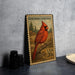 A metal stamp featuring a red cardinal perched on a branch, with a forest in the background.
