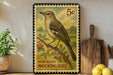 A vintage postage stamp featuring a Northern Mockingbird perched on a branch, with a kitchen counter and various kitchen utensils in the background.