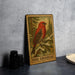 A framed illustration of a red bird, likely a pine grosbeak, perched on a branch in a forest setting, with the text "PINE GROSBEAK" below the image.