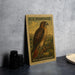 A U.S. postage stamp featuring a red-tailed hawk is displayed on a table next to some black camera lenses.
