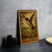 A framed illustration of a hummingbird is displayed on a wall, with a vintage stamp-like border.