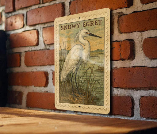 a large white egret standing in tall grass against a brick wall.