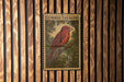A metal sign with a red bird perched on a branch, mounted on a wooden wall.