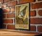 A vintage postage stamp featuring a white-breasted nuthatch is displayed on a brick wall.