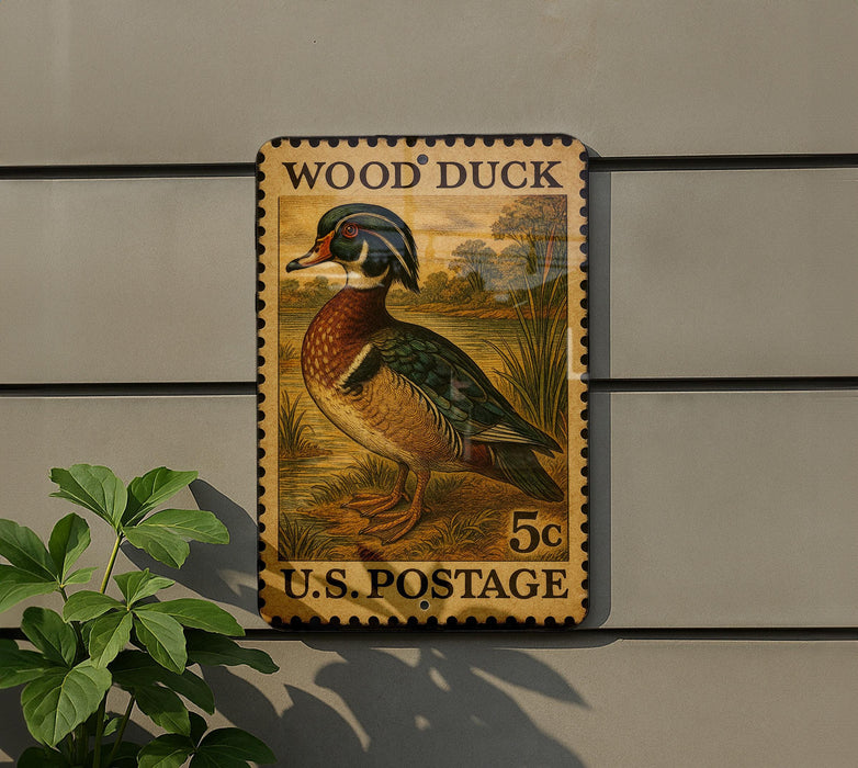 A vintage-style postage stamp featuring a wood duck, mounted on a wall next to a plant.