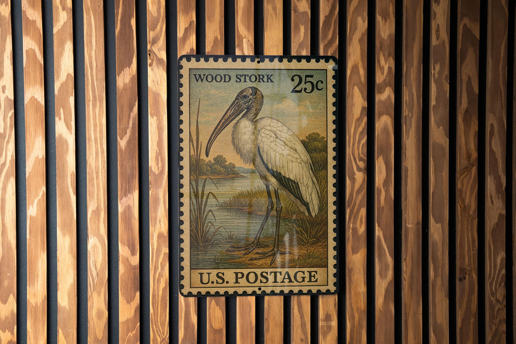 A U.S. postage stamp featuring a wood stork is displayed on a wooden wall.