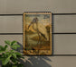 A U.S. postage stamp featuring a wood stork is displayed on a wall, with a plant to the left.