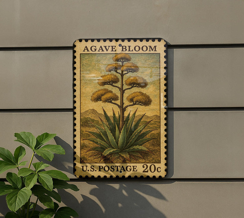 A U.S. postage stamp featuring an illustration of an agave plant, mounted on a wall next to a plant.