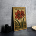 A metal sign with an illustration of a red flower and green leaves, labeled "AMARYLLIS HIPPEASTRUM", is displayed on a table next to some black camera lenses.