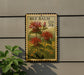 A vintage-style stamp depicting a red flower with green leaves, mounted on a wall next to a plant.