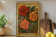 A framed illustration of a red and orange tulip plant is displayed on a shelf, accompanied by a wooden cutting board, a potted plant, and some lemons.