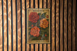 A vintage-style postage stamp featuring a floral illustration of a red rose and two orange tulips, mounted on a wooden wall.