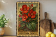 a framed illustration of red flowers, with the text "Begonia (Wax)" below the artwork. The frame is placed on a shelf next to a wooden cutting board and a potted plant.