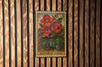 A vintage-style metal stamp featuring a vibrant illustration of red flowers against a wooden background.