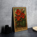 A metal plate with a vintage-style illustration of red flowers and green leaves, labeled "Begonia (Wax"), is displayed on a gray countertop next to a stack of black camera lenses.