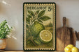 A vintage postage stamp featuring a lemon tree and a lemon slice, with the text "BERGAMOT 5c" printed on it. The stamp is displayed on a shelf next to a wooden cutting board and a potted plant.
