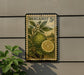 A vintage postage stamp featuring a lemon tree and a lemon slice, mounted on a wall next to a plant.
