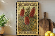 a framed vintage stamp with a floral design, placed on a shelf next to a wooden cutting board and some lemons.
