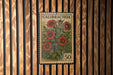 A vintage postage stamp from Calibracha, featuring a floral design with red flowers and green leaves, is displayed on a wooden wall.