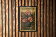 A U.S. postage stamp featuring a floral design is displayed on a wooden wall.