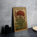 a framed illustration of a red flower, possibly a celosia, on a wall.
