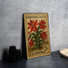 A vintage Christmas postage stamp featuring a cactus plant with red flowers, placed on a table next to some black camera lenses.