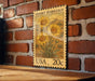 A vintage-style postage stamp featuring a desert marigold flower is displayed on a brick wall.