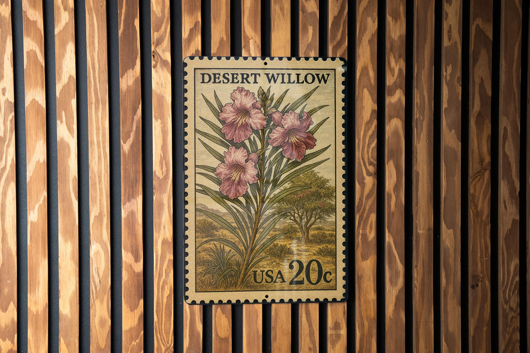 A vintage United States postage stamp featuring a desert willow plant with pink flowers, mounted on a wooden wall.