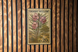 A vintage United States postage stamp featuring a desert willow plant with pink flowers, mounted on a wooden wall.